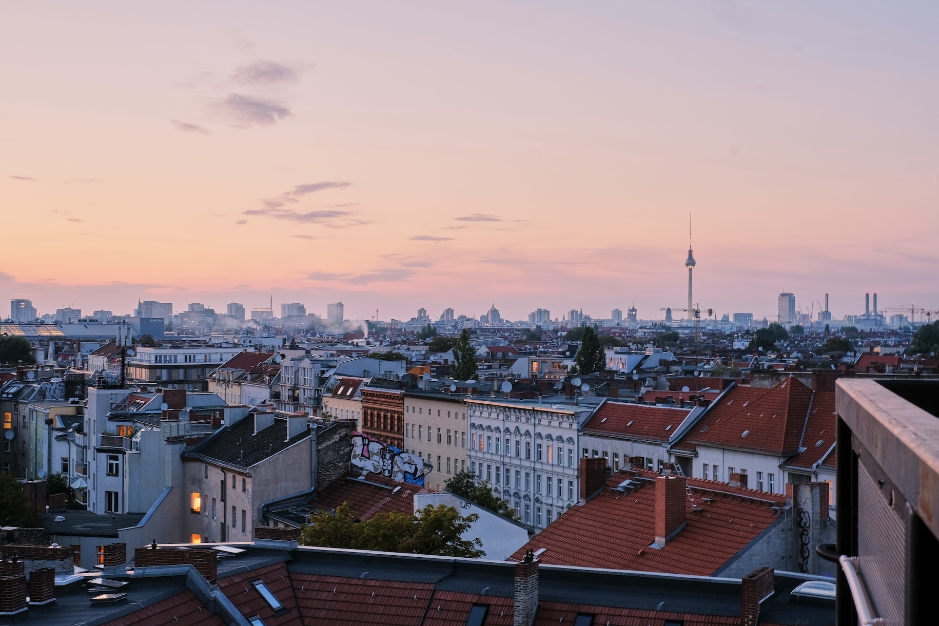 Berlin skyline at dusk, with the TV tower visible over rooftops bathed in soft pink light